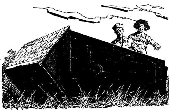 Two young, smiling, boys are on top of a solid, black object lying on the ground.