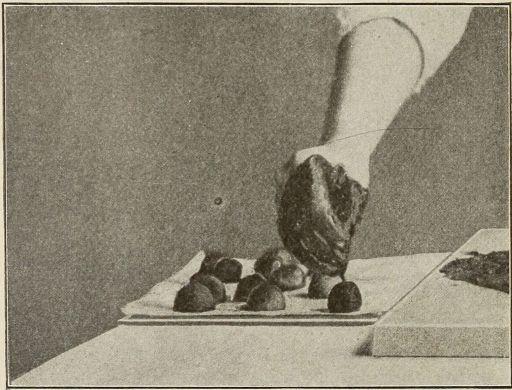 last photo of completelly chocolate -covered hand adding top decoration to bon-bons