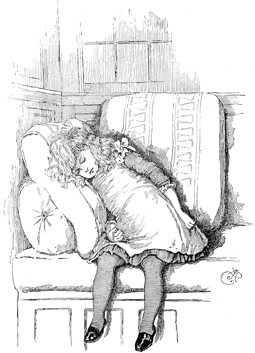 A little girl holding a string of beads in her hand is sitting on a day-bed, leaning against some cushions at the end, fast asleep.