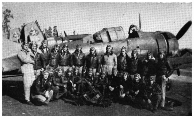 A group of men in flying gear posing in front of an airplane