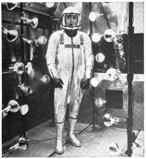 A man standing in a pressure suit surrounded by floodlights