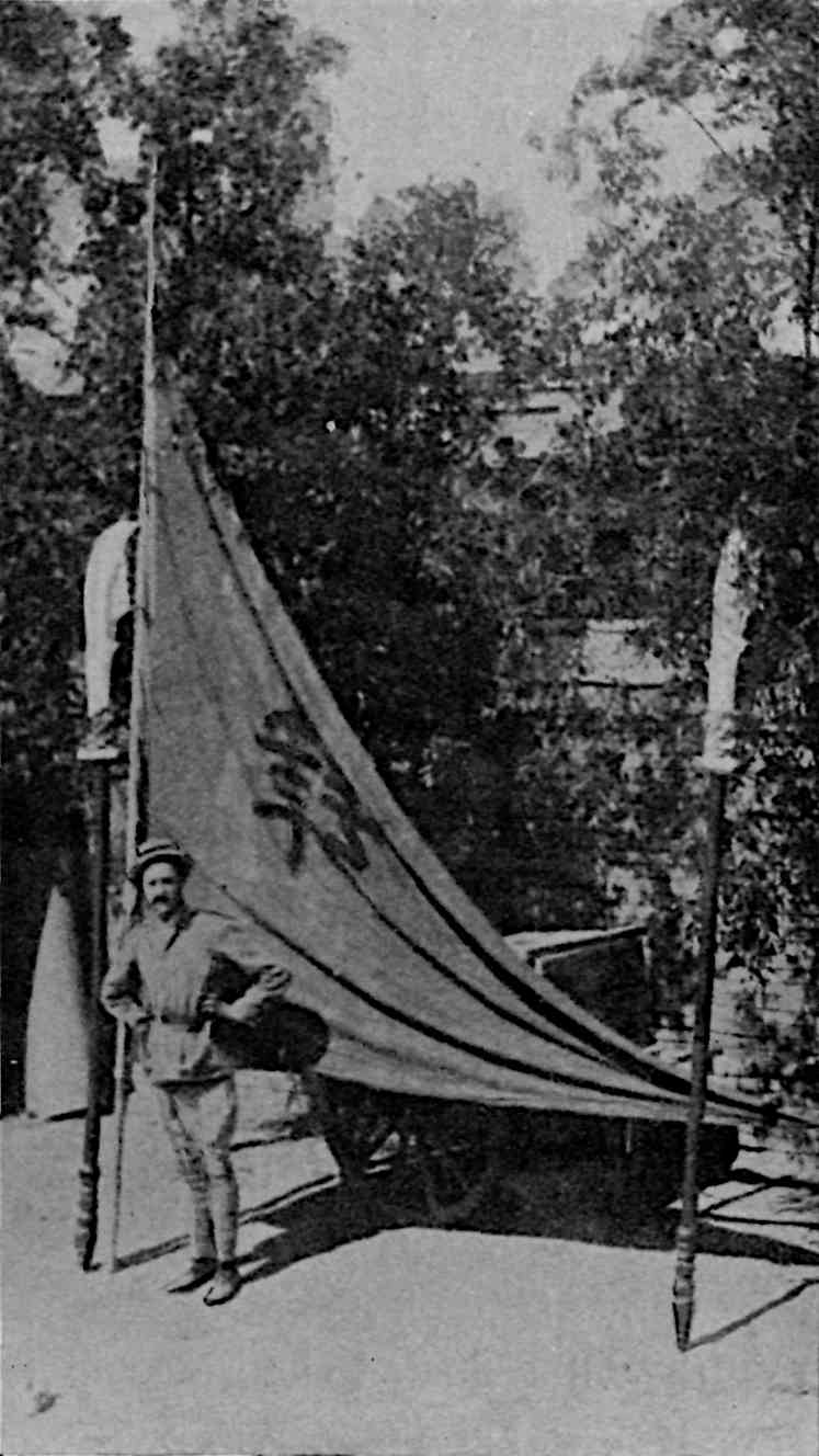 The author in front of a flag with a Chinese character upon it
