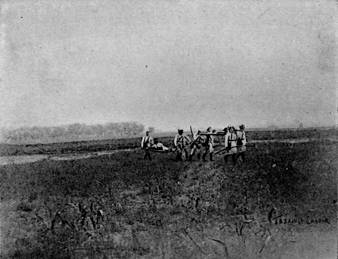 Several people carrying a few stretchers in a field